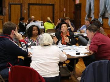 Adults holding discussions at three round tables