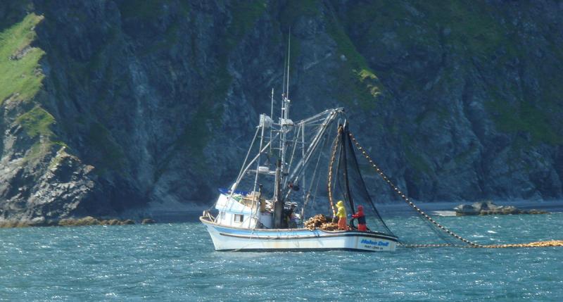 Fishing boat on water in front of cliffs