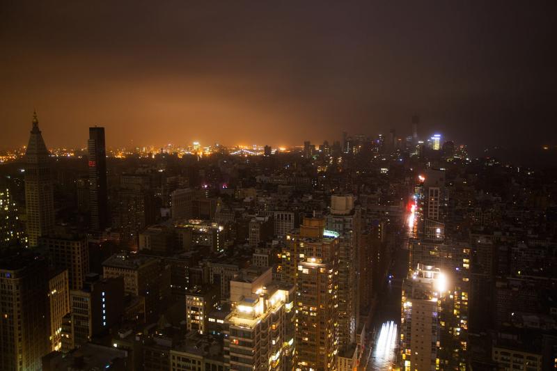 Nightime photo of dense city buildings, many of which are dark