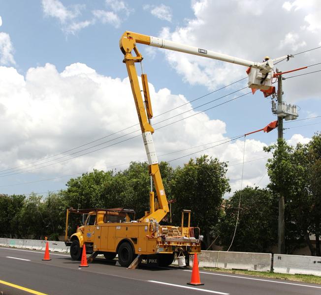 Photo of utility worker repairing raised electical lines