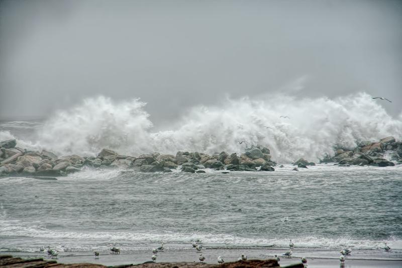 Large waves crashing on rocks offshore from a beach